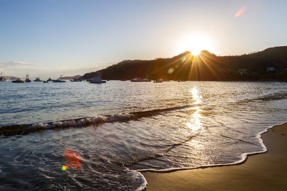 sun peeking from behind the mountain on Playa del Coco Costa Rica
