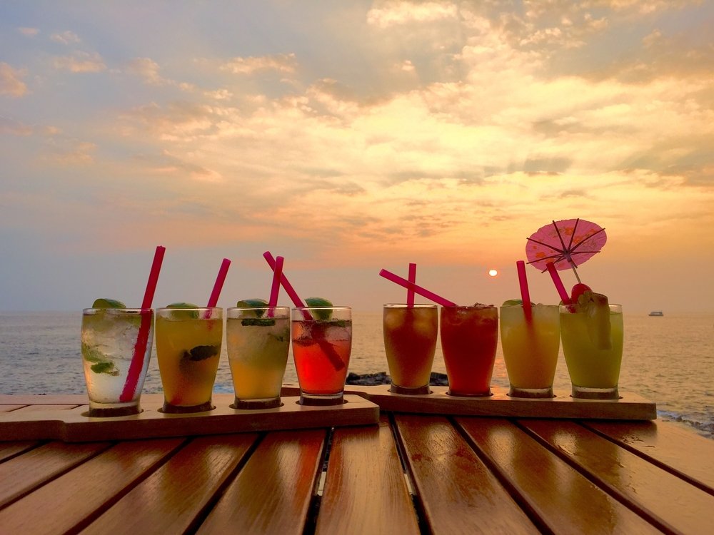row of happy hour drinks by the beach