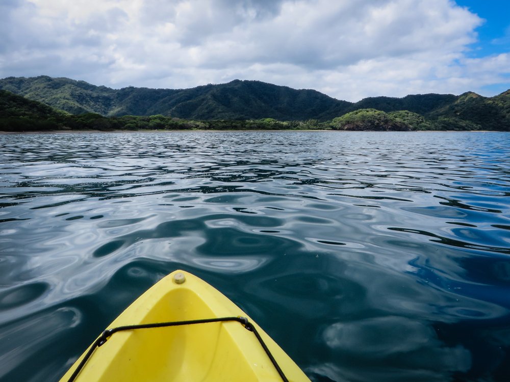 tip of yellow kayak with green mountains